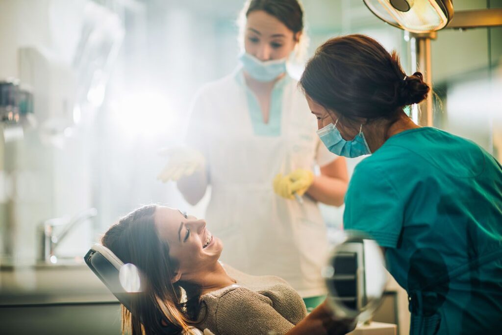 Smiling woman sitting in dentist chair and talking to her dentist before teeth examination preventative dentistry dentist in Boulder Colorado